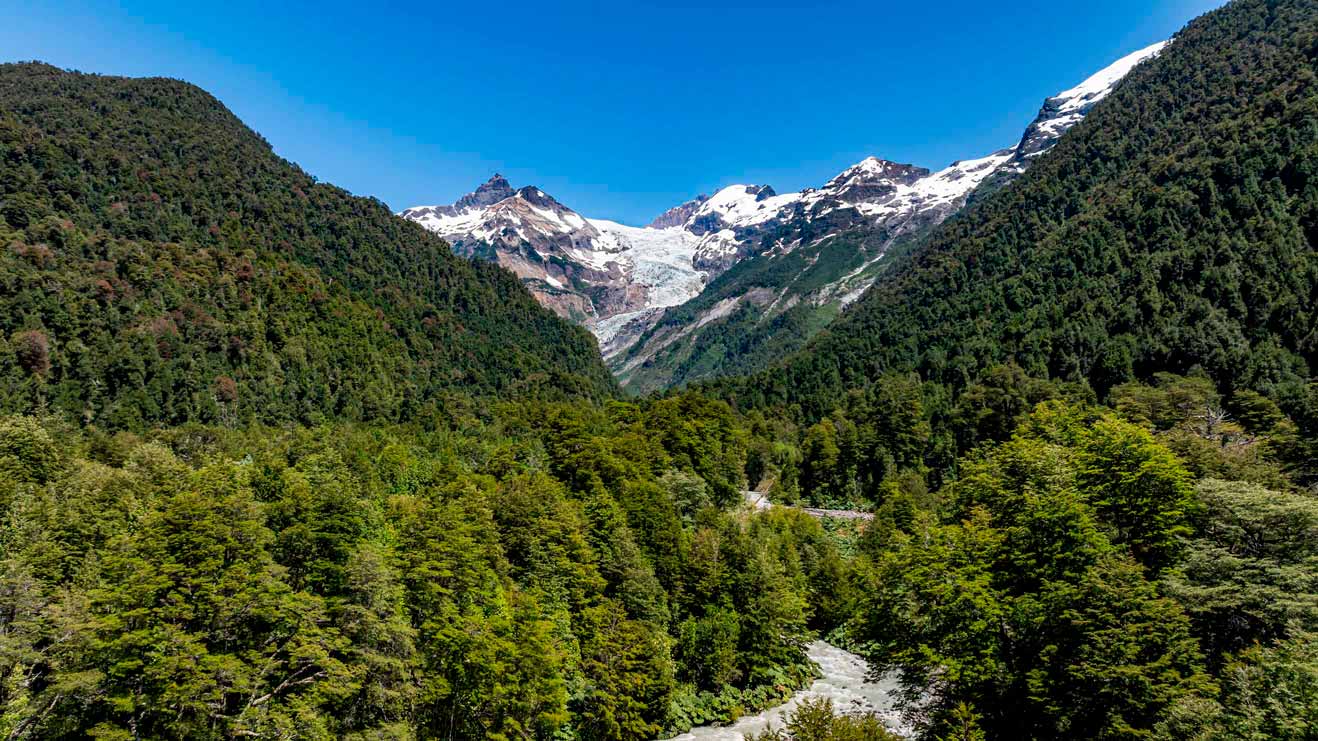 Current image: Glacier and forested mountains with a river in a Chilean natural reserve.