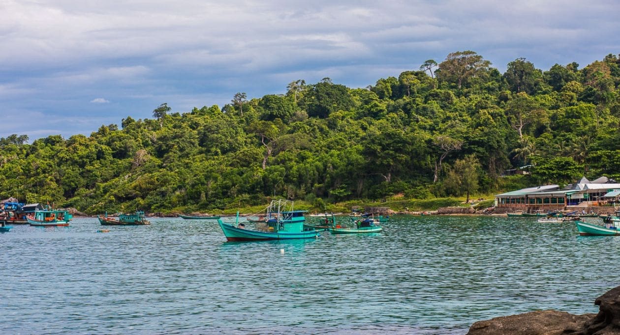 Fishing boats anchored in the waters off Phu Quoc, with a lush tropical forest along the shoreline